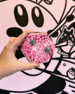 Hand holding a pink spider web container with cartoon character in the background
