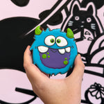 Hand holding a blue monster-shaped object with a black and white background